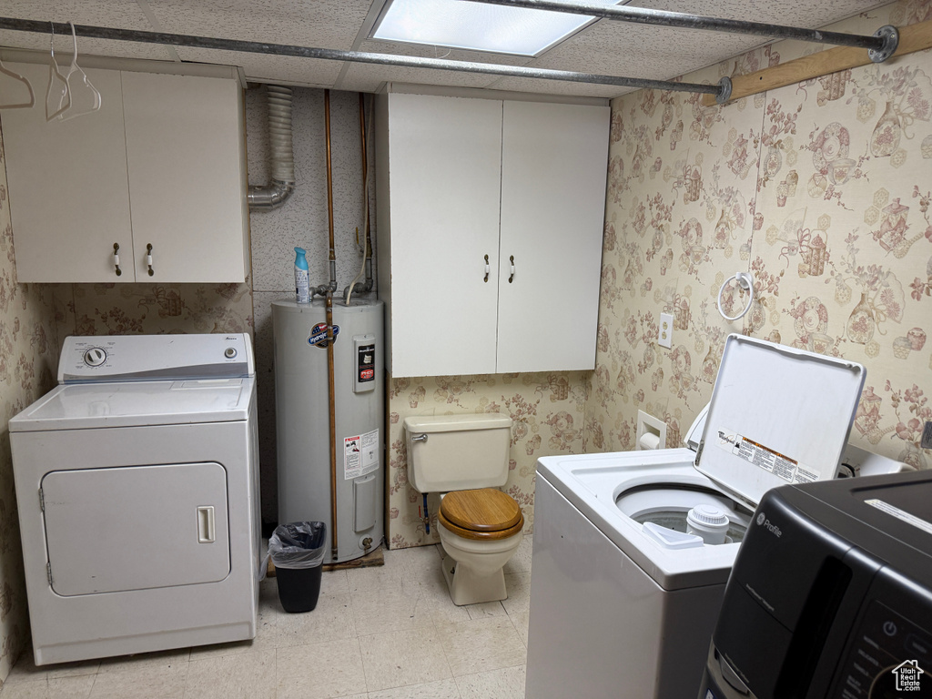 Washroom with electric water heater, washer and dryer, wallpapered walls, and light flooring