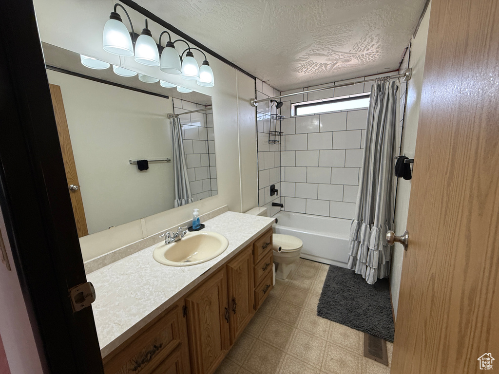 Full bath with a textured ceiling, vanity, toilet, shower / bath combo with shower curtain, and tile patterned floors