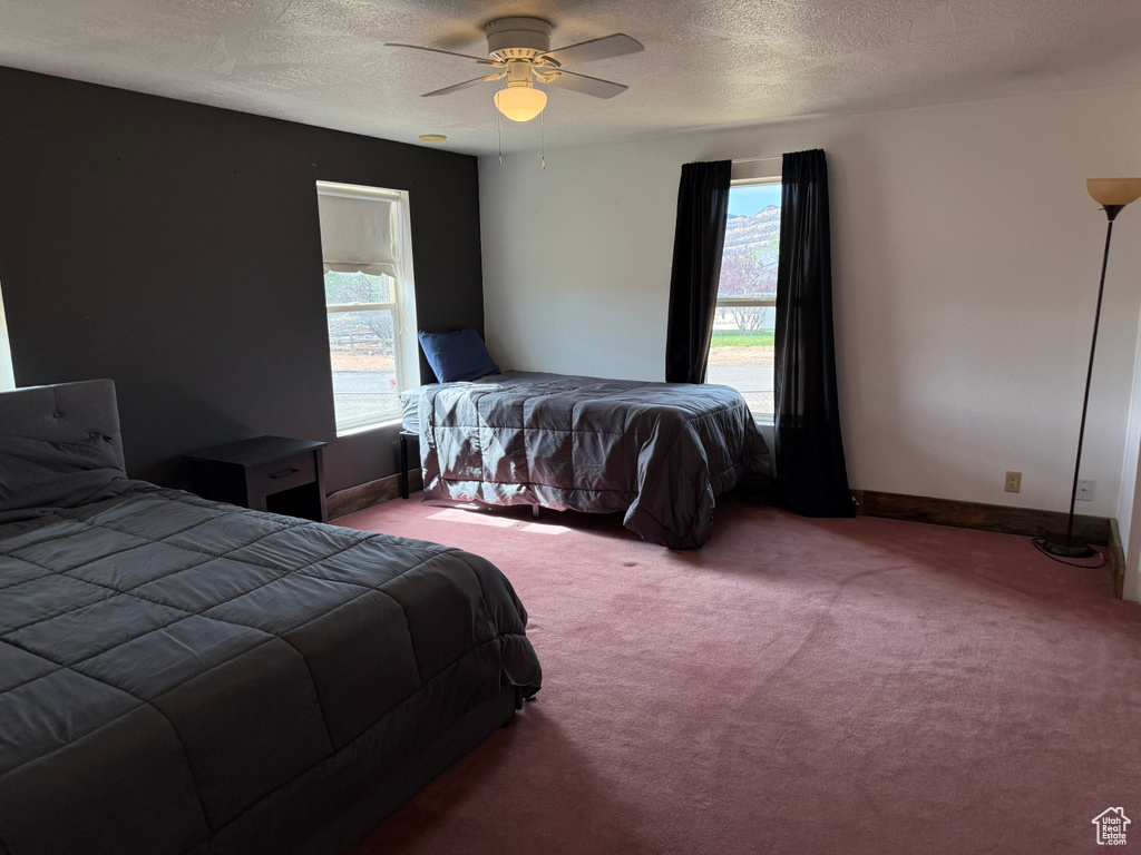 Bedroom featuring carpet floors, a textured ceiling, a ceiling fan, and baseboards