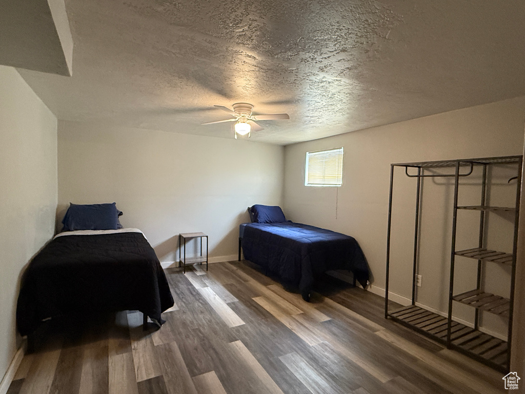 Bedroom featuring a textured ceiling, wood finished floors, baseboards, and a ceiling fan