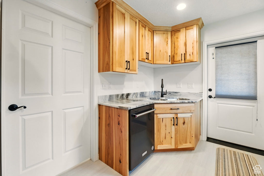 Kitchen with black dishwasher, a sink, light stone countertops, light wood finished floors, and recessed lighting