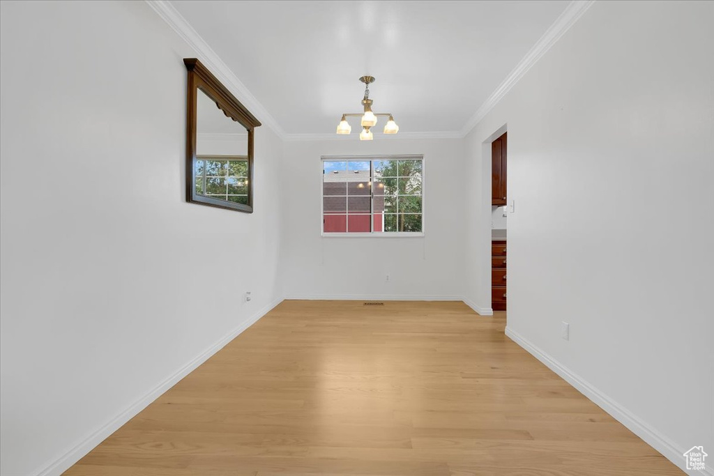 Unfurnished room featuring light wood-style floors, a chandelier, and ornamental molding