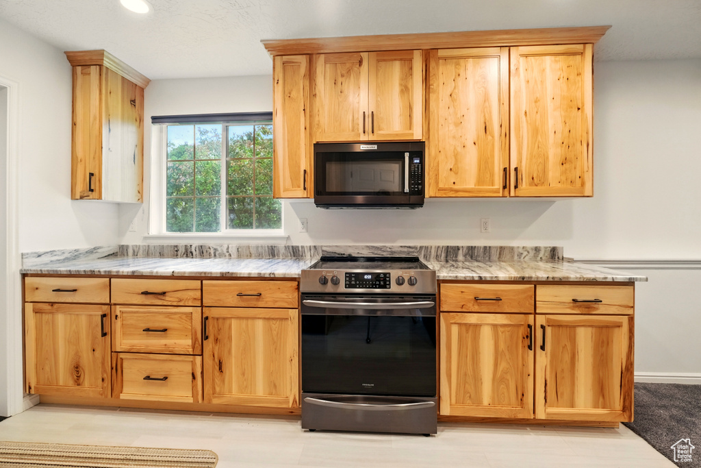Kitchen featuring stainless steel range with electric cooktop, light stone counters, and recessed lighting
