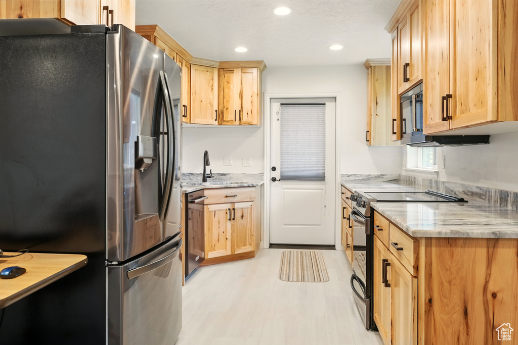 Kitchen with black appliances, light brown cabinets, light wood finished floors, a sink, and recessed lighting