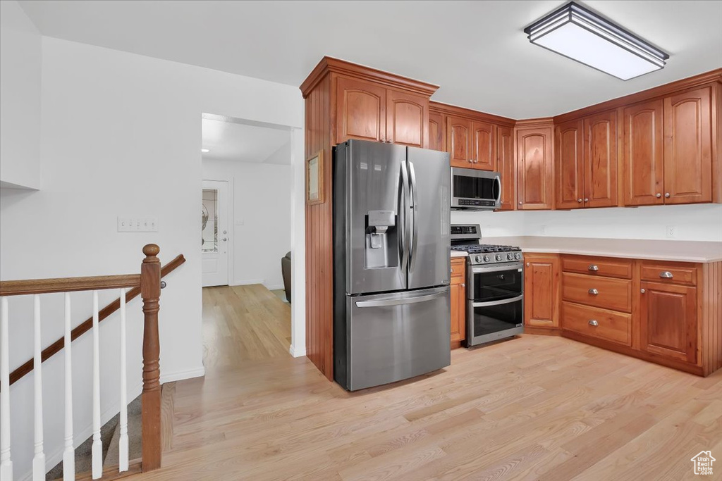 Kitchen featuring appliances with stainless steel finishes, light wood-style flooring, brown cabinets, and light countertops