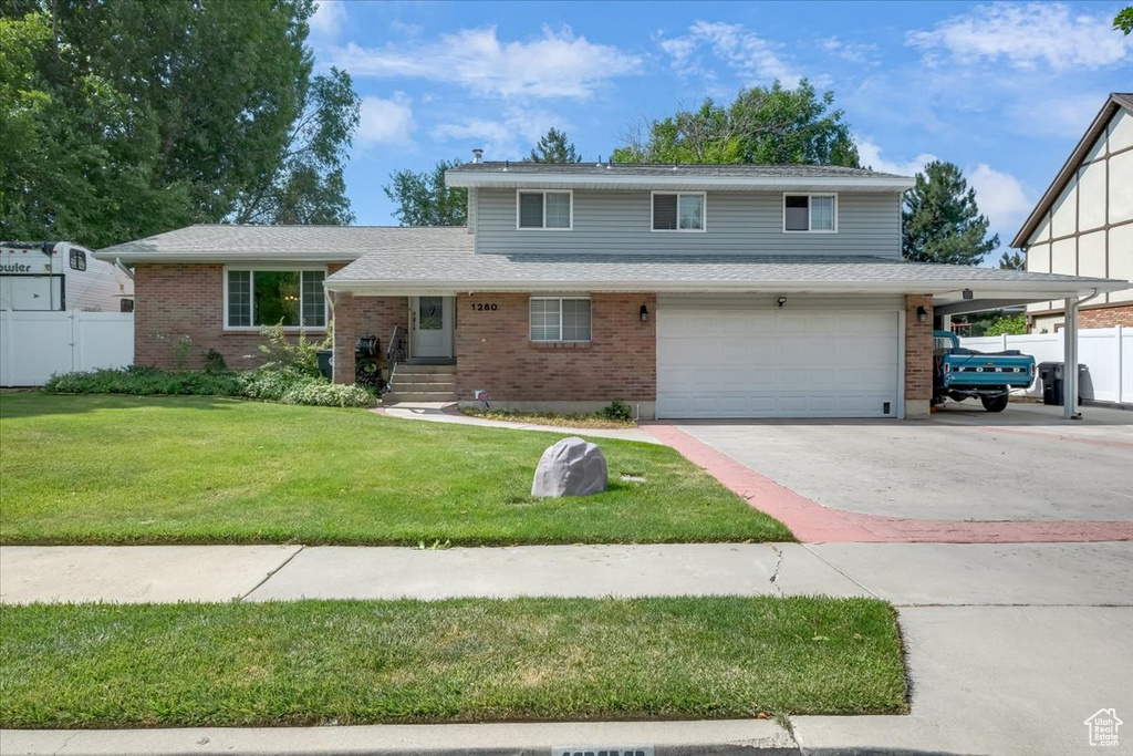 Tri-level home featuring a garage, brick siding, and driveway