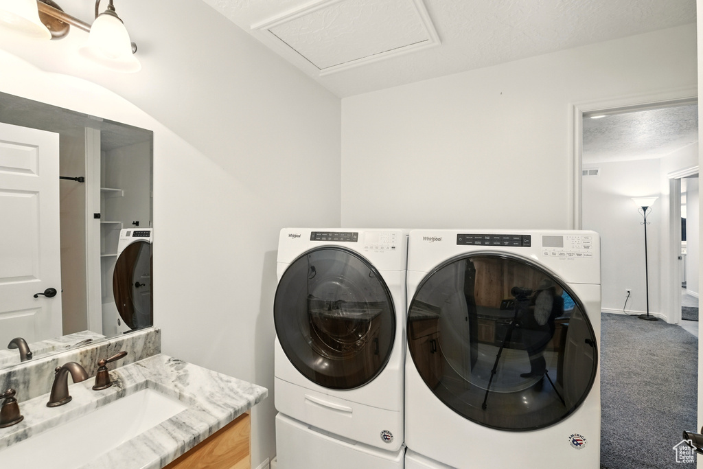 Washroom featuring a sink, independent washer and dryer, carpet, and baseboards