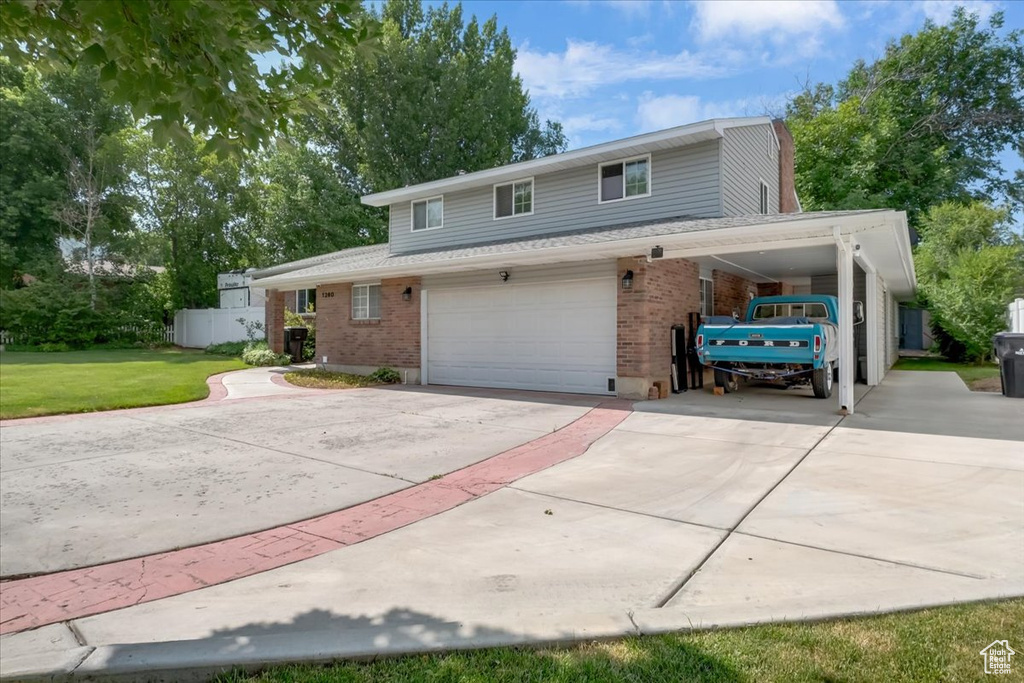 View of front of home with driveway, brick siding, a garage, and a front lawn