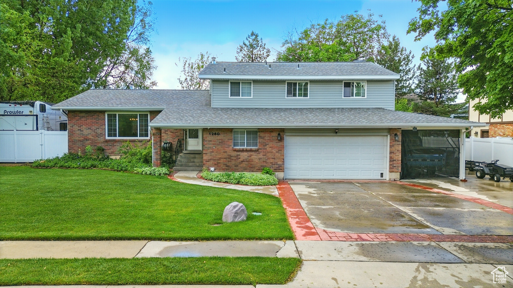 Split level home with an attached garage, brick siding, driveway, and roof with shingles
