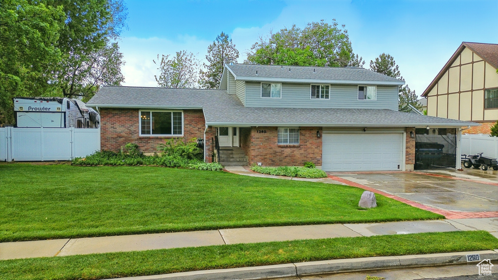 Tri-level home featuring brick siding, concrete driveway, an attached garage, and a shingled roof