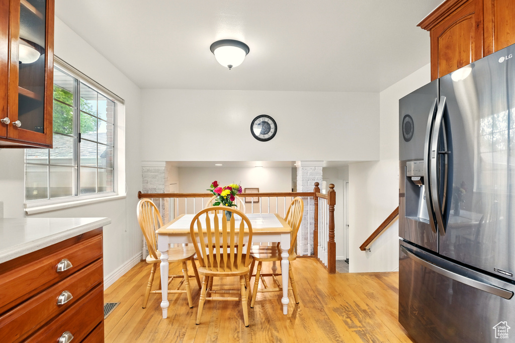 Dining area featuring light wood finished floors, ornate columns, and baseboards