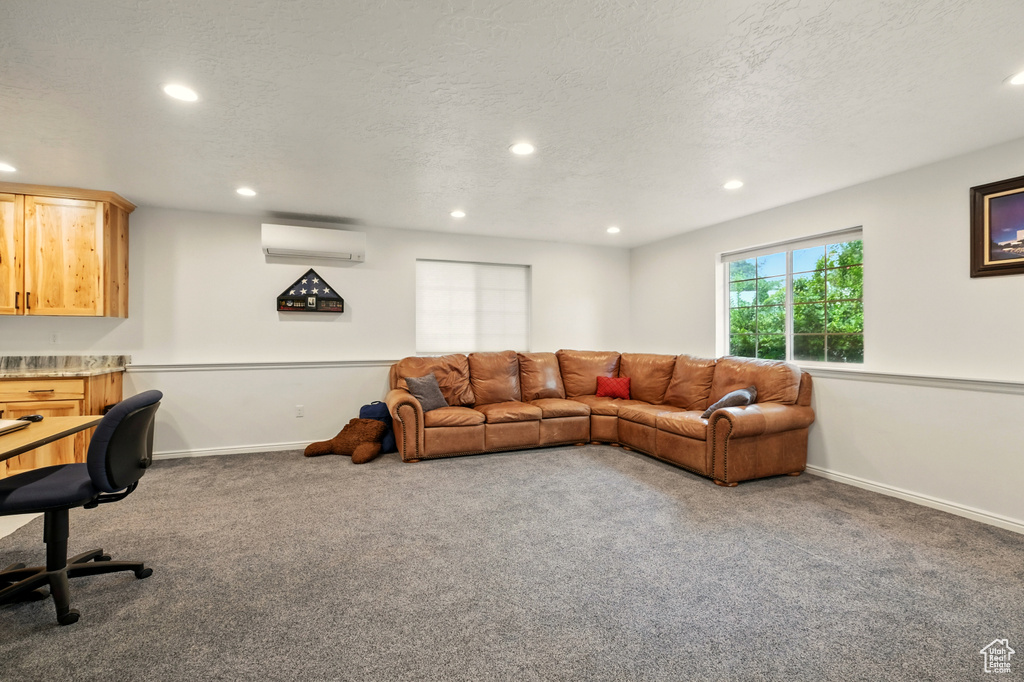 Living area featuring a wall mounted air conditioner, carpet floors, recessed lighting, a textured ceiling, and baseboards