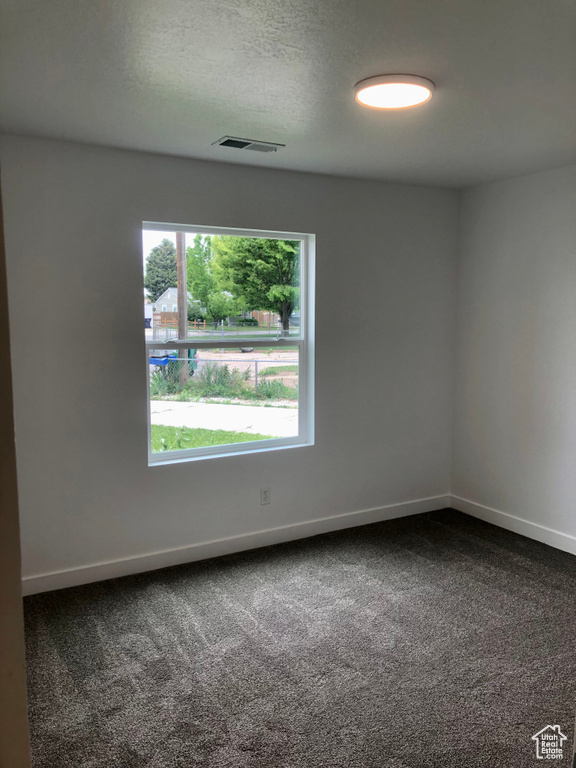 Empty room featuring dark carpet and baseboards