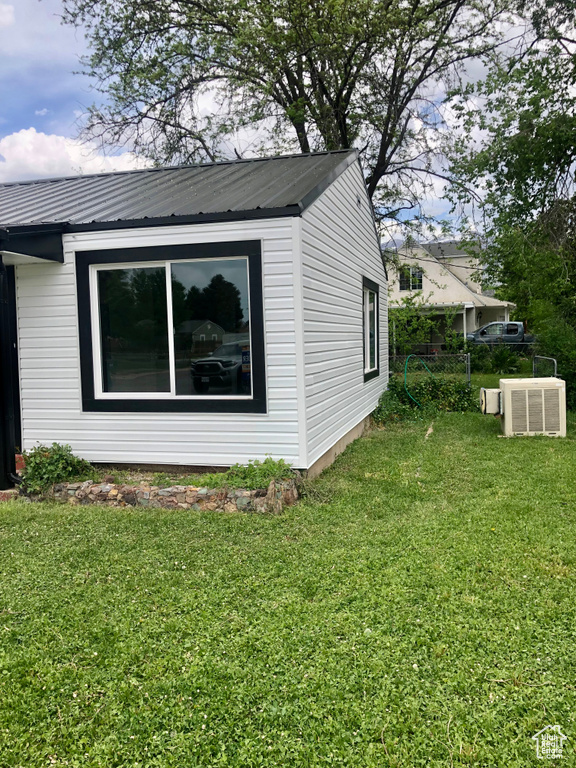 View of property exterior with metal roof and a yard