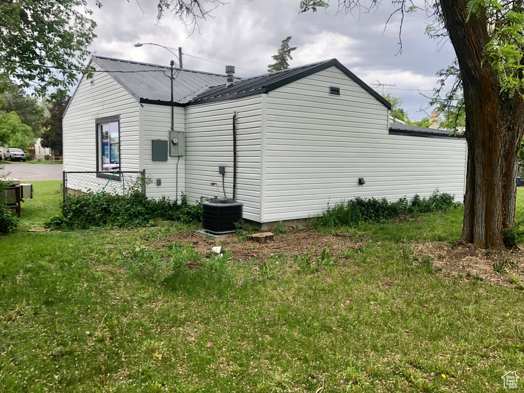 View of home\'s exterior with metal roof, a yard, and cooling unit