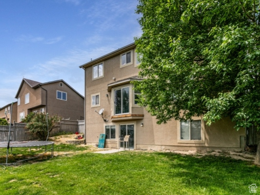 Rear view of house with a trampoline and stucco siding