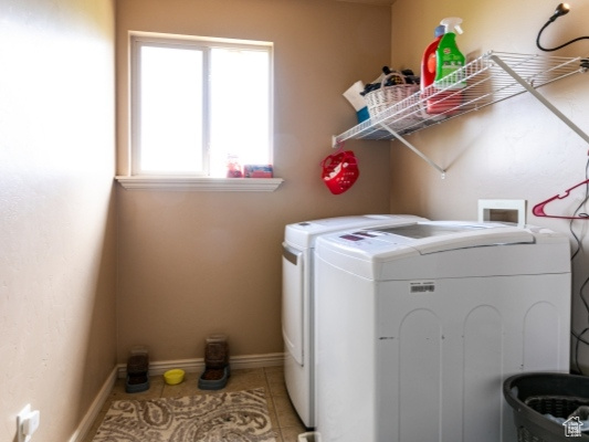 Laundry room with washer and clothes dryer, plenty of natural light, light tile patterned flooring, and baseboards