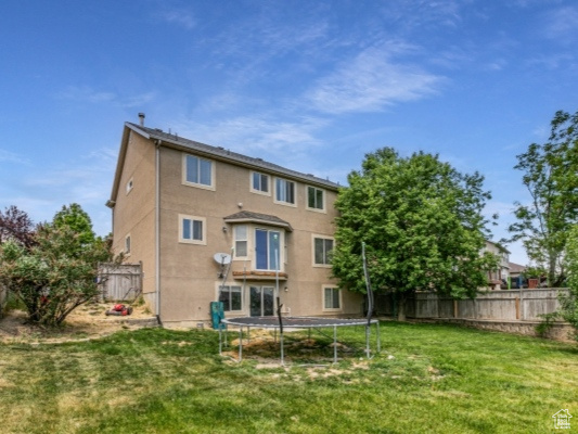 Rear view of house featuring a trampoline and stucco siding