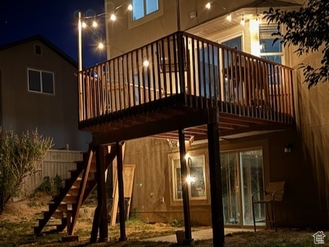Back of house at twilight with stairway, a wooden deck, and a lawn