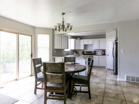 Dining space with a chandelier, baseboards, and light tile patterned floors