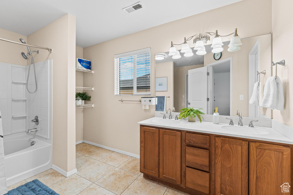 Bathroom featuring tile patterned floors, double vanity, washtub / shower combination, and baseboards