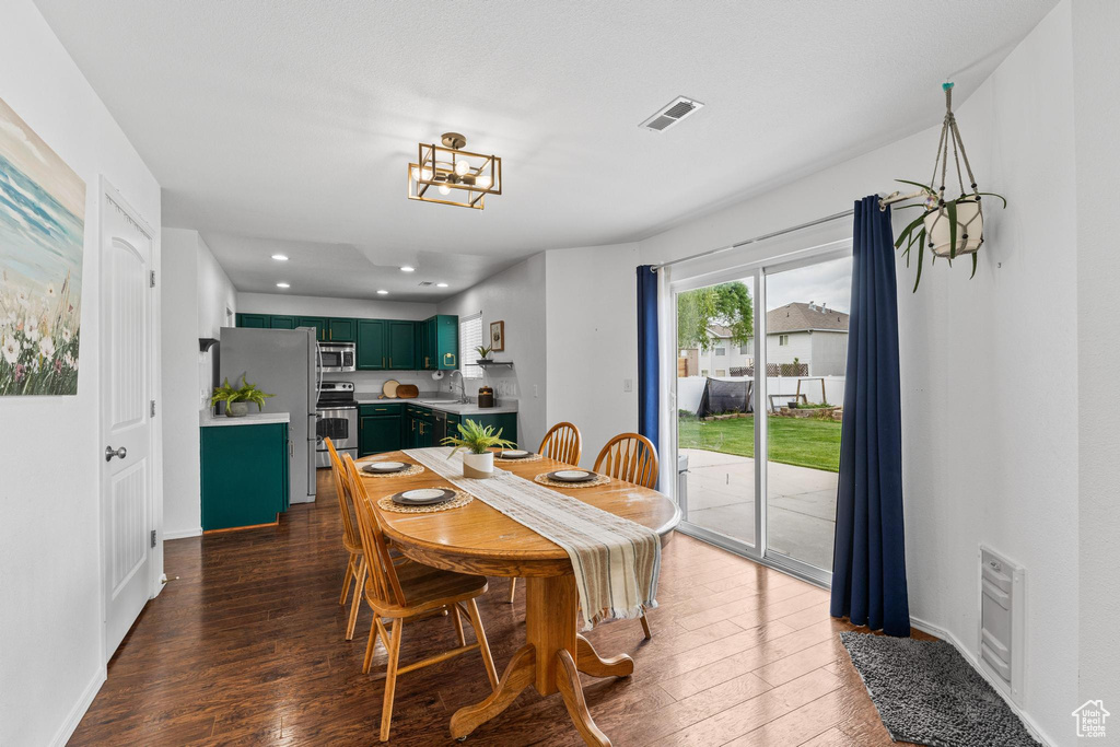 Dining room with dark wood-type flooring, a chandelier, baseboards, and recessed lighting