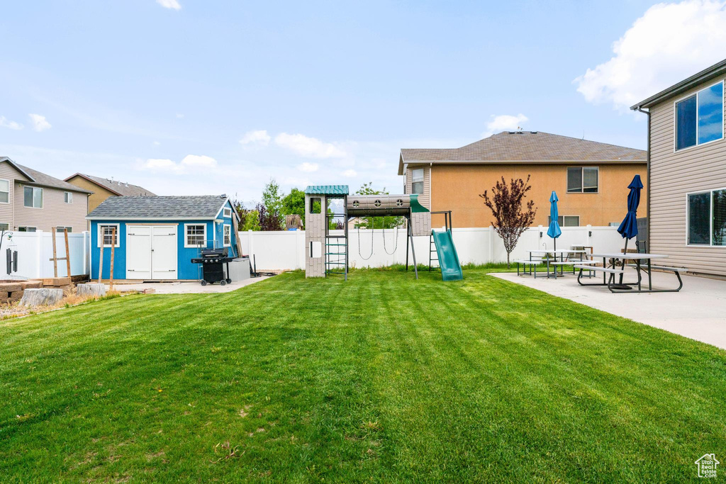 View of yard featuring a playground, a storage unit, an outbuilding, and a patio