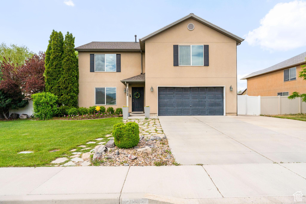 View of front of property featuring a garage, stucco siding, and driveway