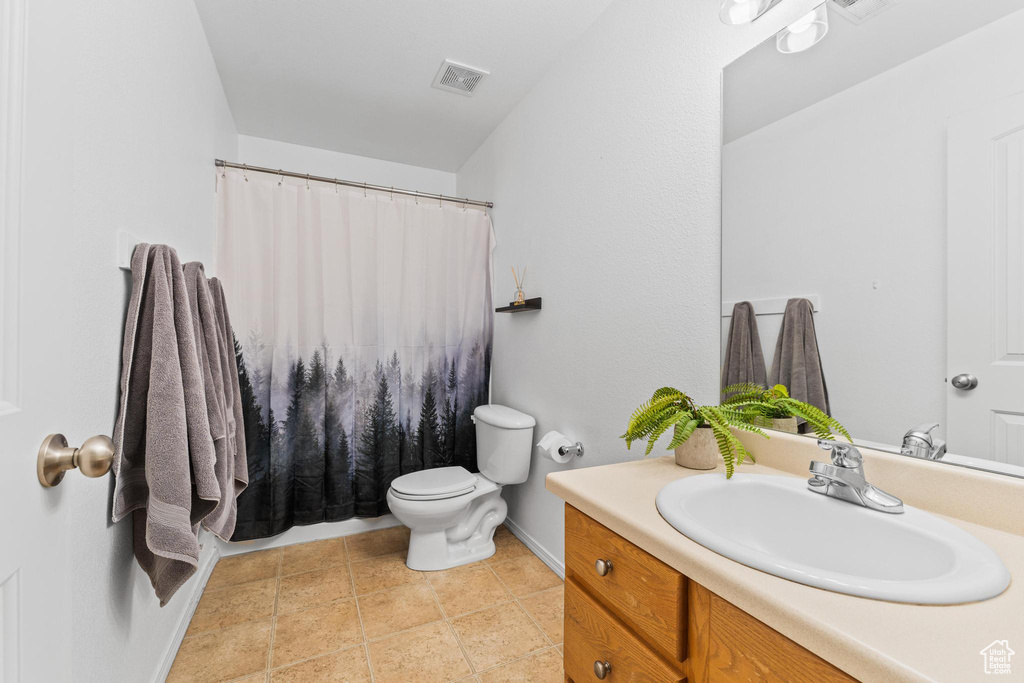 Bathroom with toilet, vanity, baseboards, and a shower with shower curtain