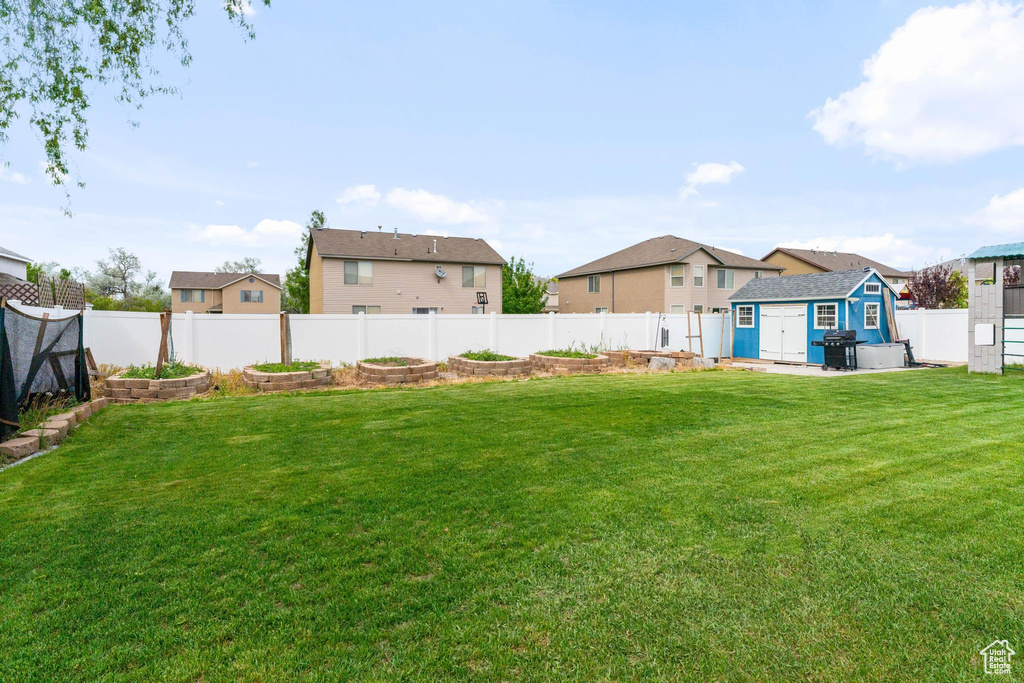 View of yard with a vegetable garden, a shed, a residential view, and an outbuilding