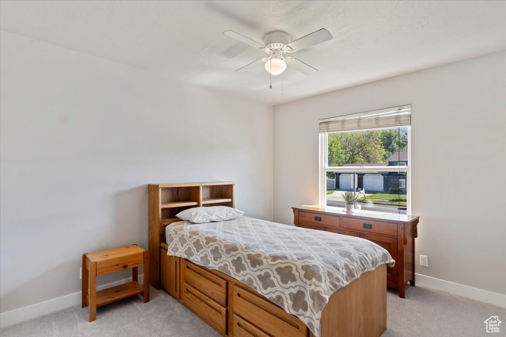 Bedroom featuring light carpet, baseboards, and a ceiling fan