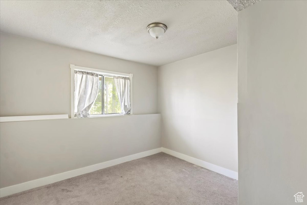 Spare room with a textured ceiling, carpet floors, and baseboards