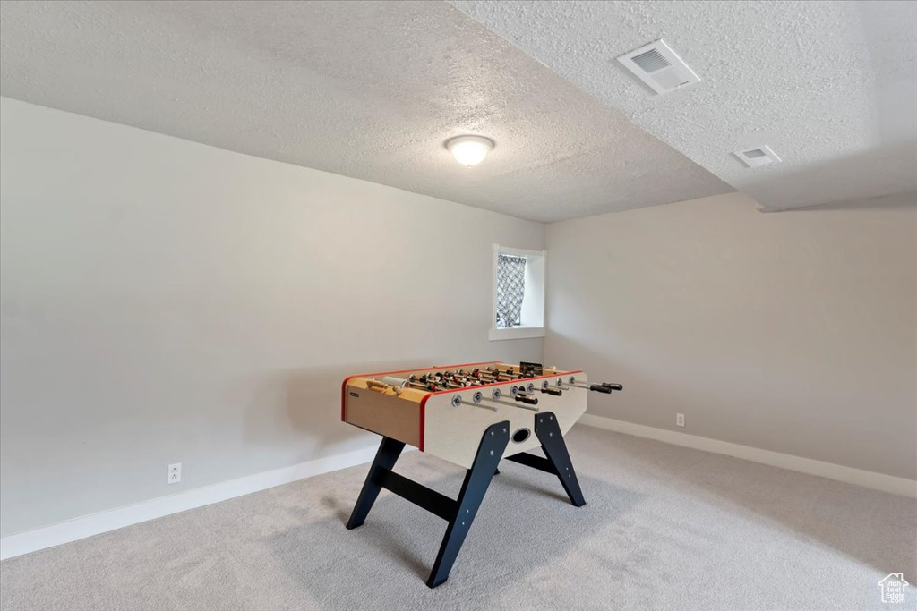 Rec room with a textured ceiling, carpet flooring, and baseboards
