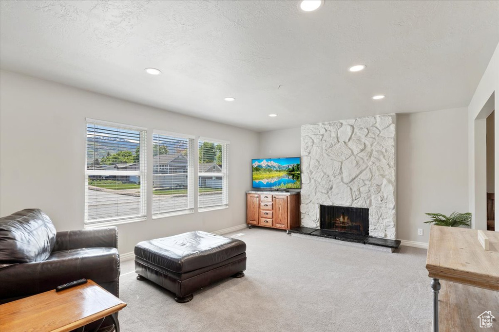 Living area with carpet floors, a stone fireplace, baseboards, and recessed lighting