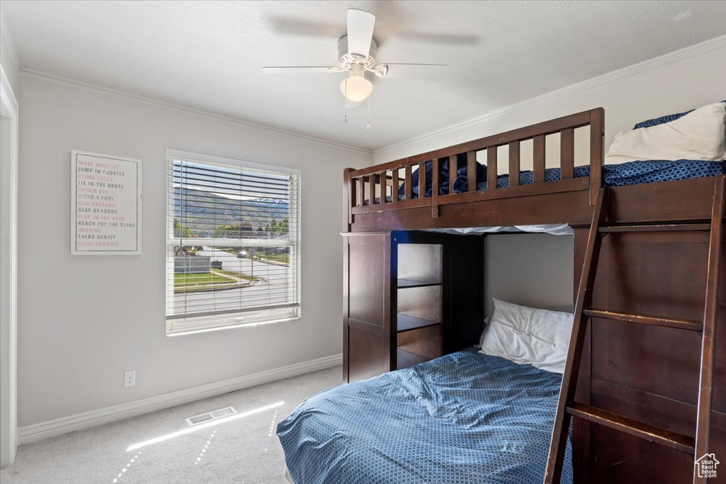 Carpeted bedroom with crown molding, baseboards, and ceiling fan