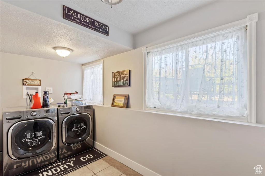 Washroom with separate washer and dryer, a textured ceiling, baseboards, and tile patterned flooring