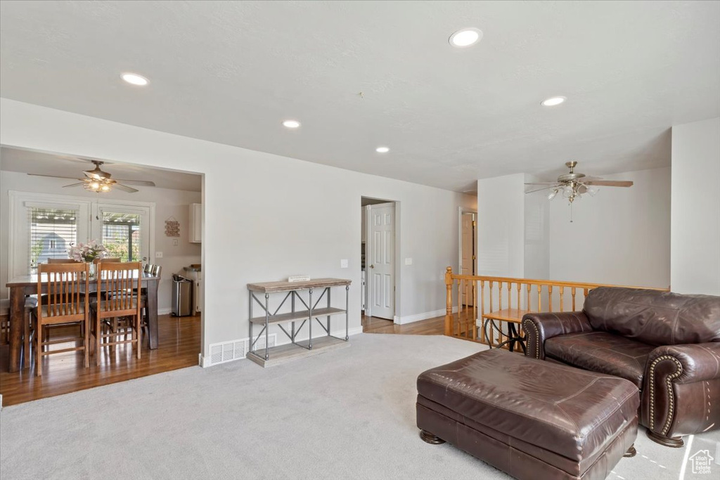 Living area with a ceiling fan, recessed lighting, light colored carpet, and baseboards