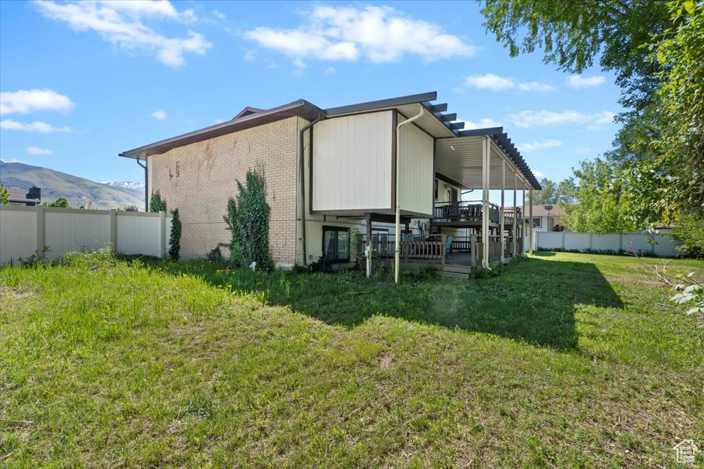 Back of house with brick siding and a deck with mountain view
