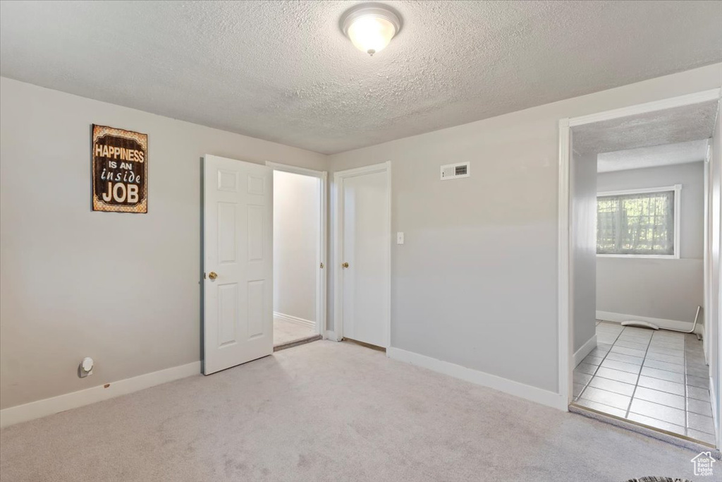 Unfurnished bedroom with a textured ceiling, baseboards, and carpet flooring
