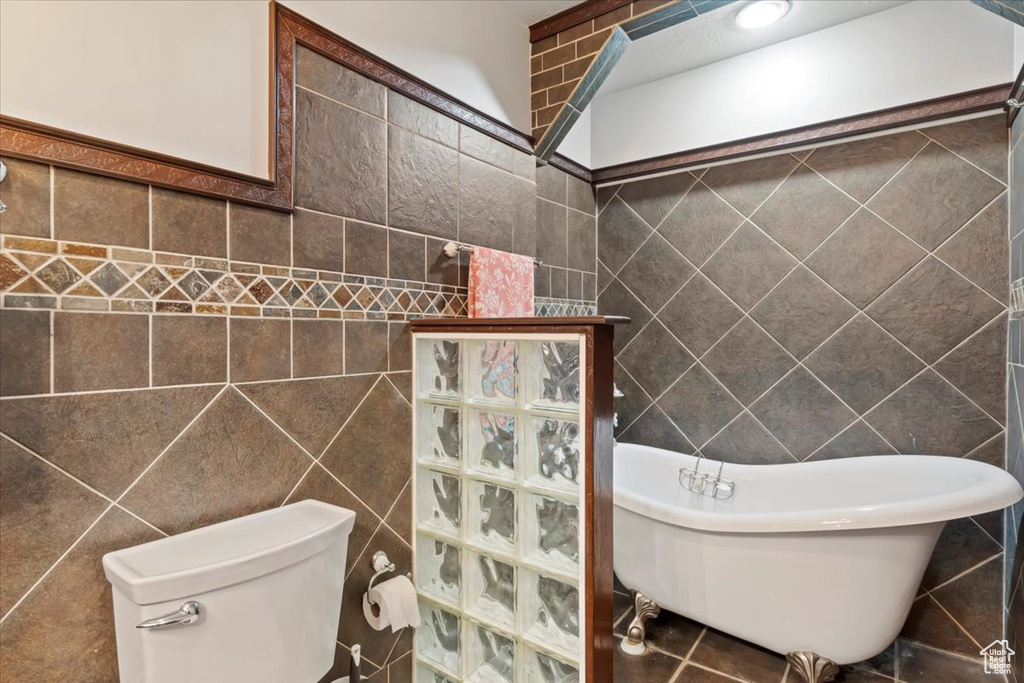 Full bath with tile walls, a soaking tub, toilet, and a walk in shower