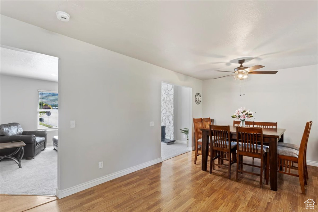 Dining area with light wood finished floors, a ceiling fan, and baseboards