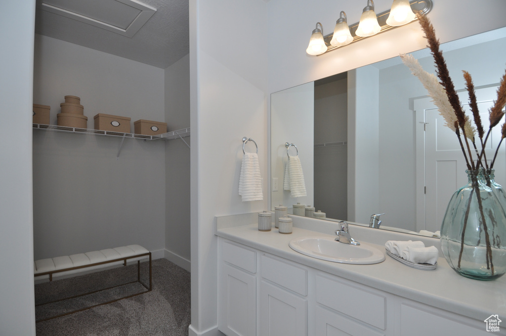 Bathroom featuring vanity, a walk in closet, and baseboards