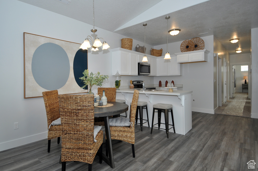 Dining room featuring a chandelier, dark wood-style flooring, vaulted ceiling, and baseboards