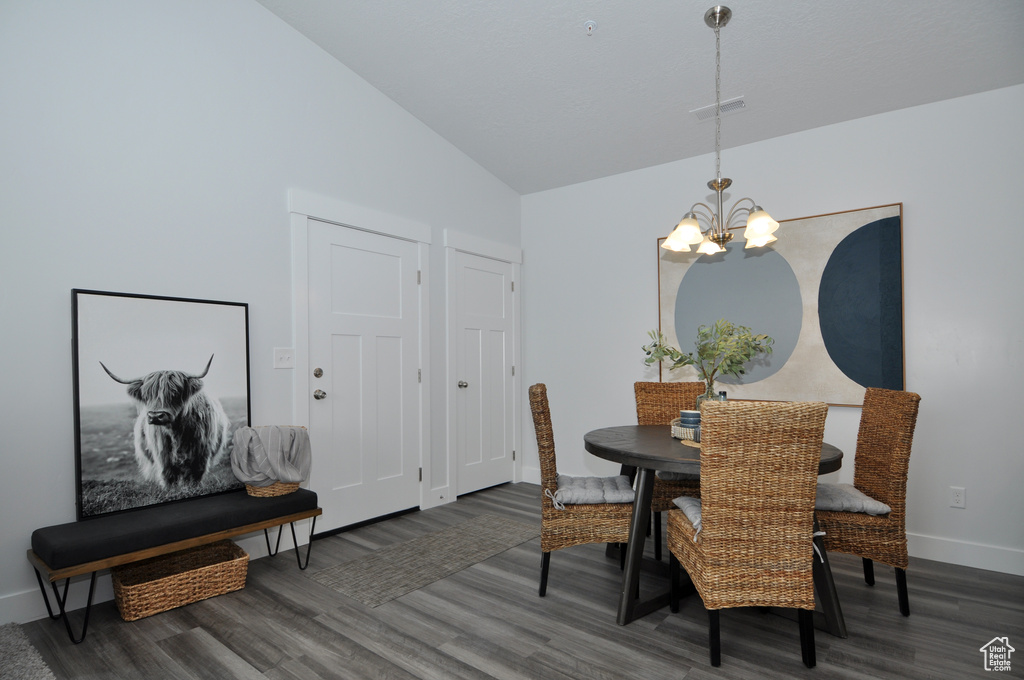 Dining space with a chandelier, wood finished floors, baseboards, and high vaulted ceiling
