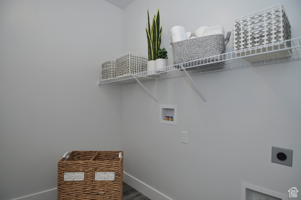 Washroom with hookup for an electric dryer, washer hookup, baseboards, and wood finished floors