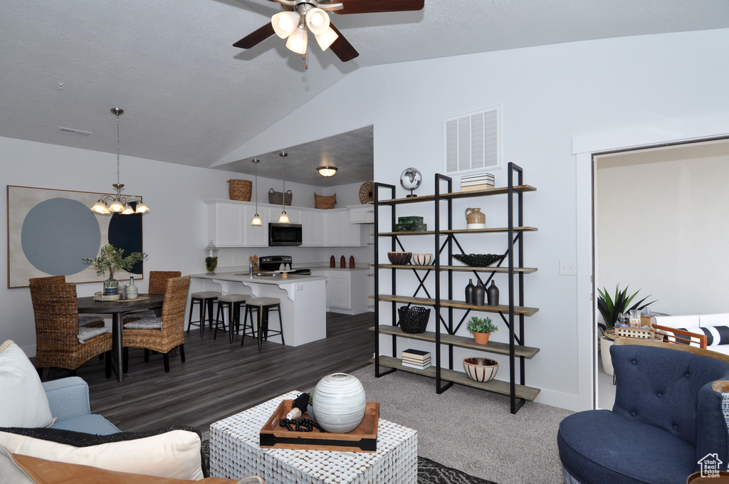 Living area featuring vaulted ceiling, a ceiling fan, a chandelier, and baseboards