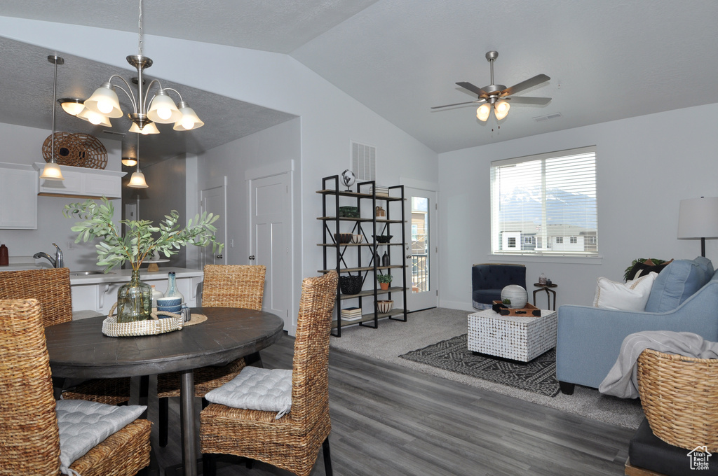 Dining space featuring vaulted ceiling, a chandelier, wood finished floors, ceiling fan, and baseboards