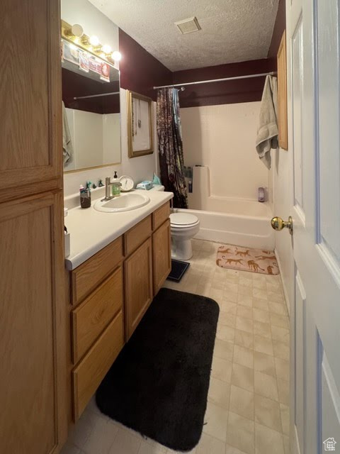Full bathroom with toilet, shower / bathtub combination with curtain, a textured ceiling, and vanity