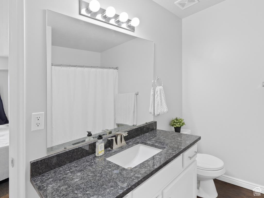 Full bathroom featuring vanity, toilet, baseboards, and wood finished floors