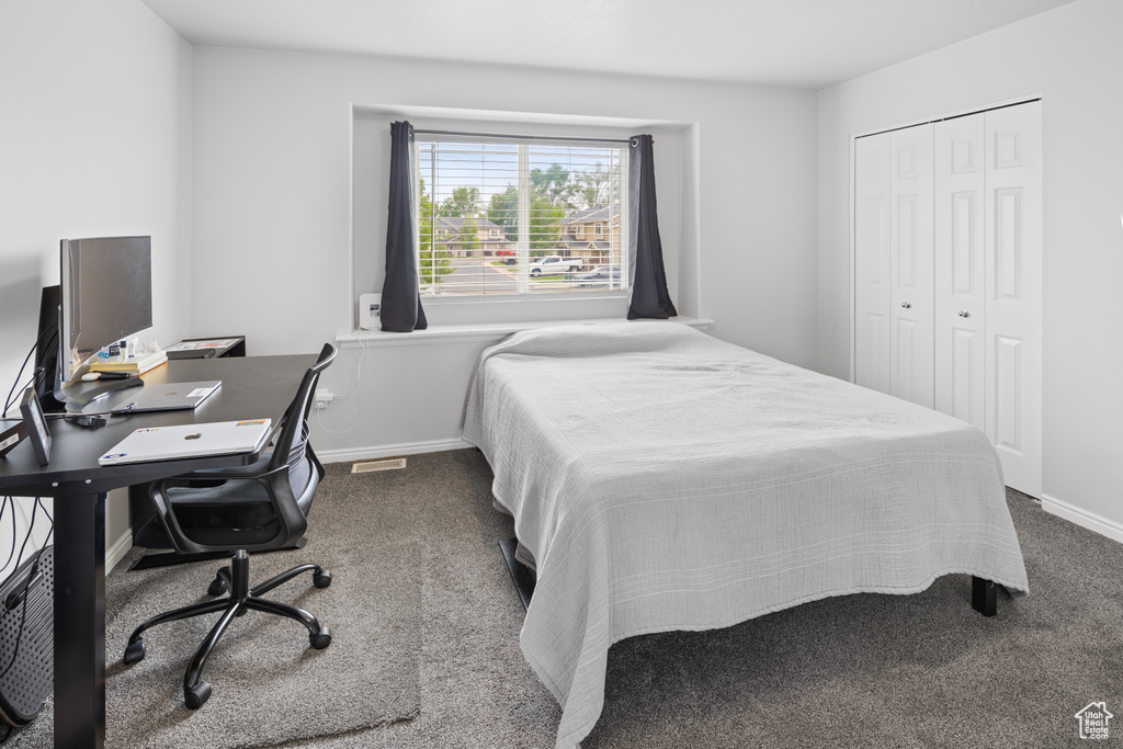 Carpeted bedroom featuring a closet and baseboards